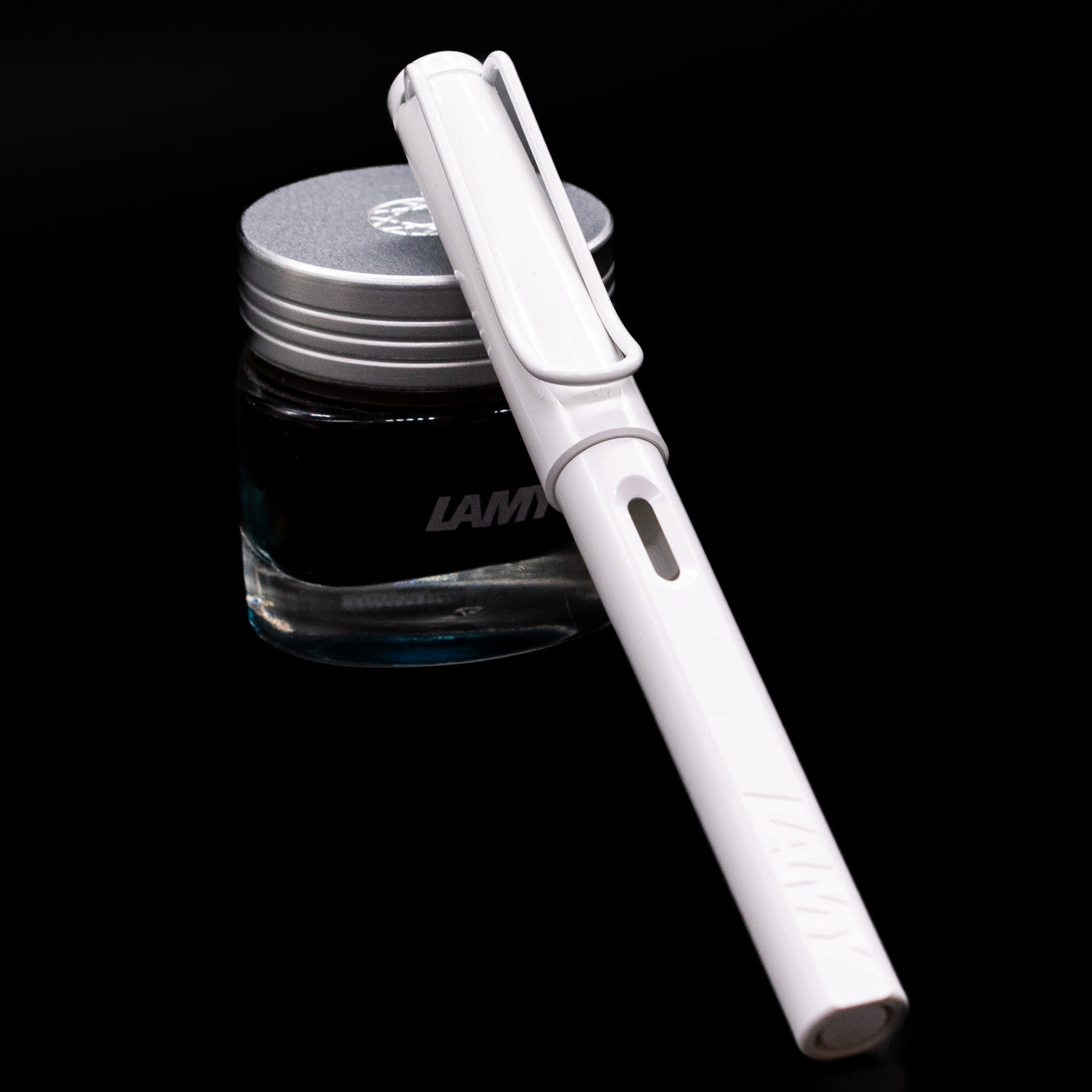 LAMY Safari Multi Fountain Pen in glossy white, capped, resting diagonally on an ink bottle.