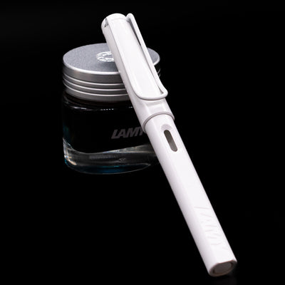 LAMY Safari Multi Fountain Pen in glossy white, capped, resting diagonally on an ink bottle.