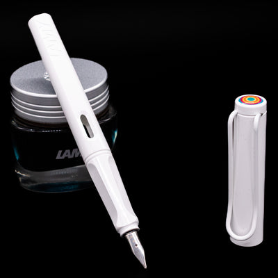 Glossy white LAMY Safari Multi pen with nib exposed, uncapped, leaning against an ink bottle.