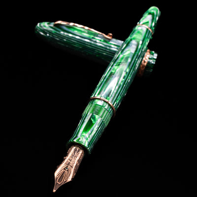Leonardo Cigar Leonardo Verde Celluloid Fountain Pen laying across its own cap, crossed, with a focus on the nib.