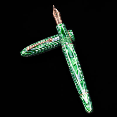 Leonardo Cigar Leonardo Verde Celluloid Fountain Pen laying on top of its cap in a crossed position showing full view of the entire uncapped pen.