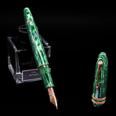 Leonardo Cigar Leonardo Verde Celluloid Fountain Pen leaning on an ink bottle uncapped showcasing the detailing on the nib.
