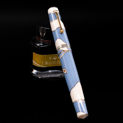 Leonardo Momento Zero Lavanda Gold Trim Fountain Pen - Preowned capped, leaning against an ink bottle. 