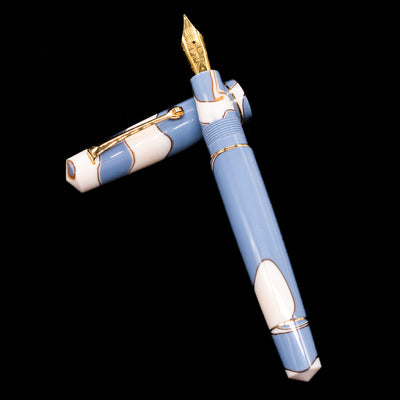 Leonardo Momento Zero Lavanda Gold Trim Fountain Pen - Preowned laying on top of its cap in a crossed position showing full view of the entire uncapped pen.