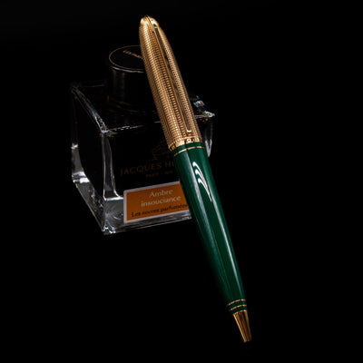 Louis Vuitton Doc Lacquer Green & Gold Ballpoint Pen - Preowned leaning on an ink bottle.