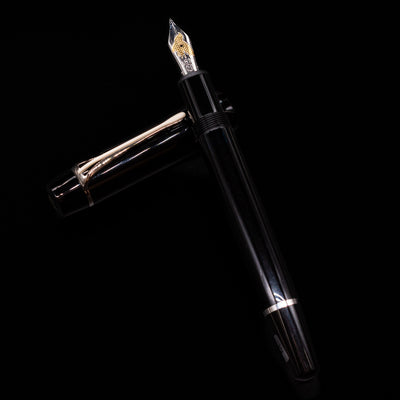 Montblanc Donation Herbert von Karajan Fountain Pen - Preowned laying on top of its cap in a crossed position showing full view of the entire uncapped pen.
