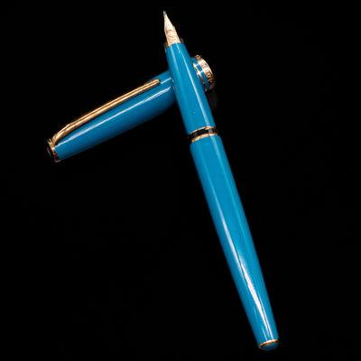 Montblanc Generation Turquoise Fountain Pen - Preowned laying on top of its cap in a crossed position showing full view of the entire uncapped pen.