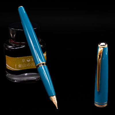 Montblanc Generation Turquoise Fountain Pen - Preowned leaning on an ink bottle uncapped showcasing the detailing on the nib.