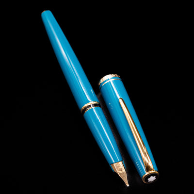  A full view of the Montblanc Generation Turquoise Fountain Pen - Preowned uncapped, with its cap laying next to the pen. 