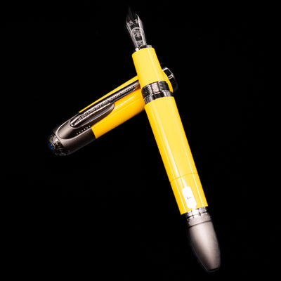 Montblanc Great Characters Enzo Ferrari Fountain Pen - Giallo Modena laying on top of its cap in a crossed position showing full view of the entire uncapped pen.