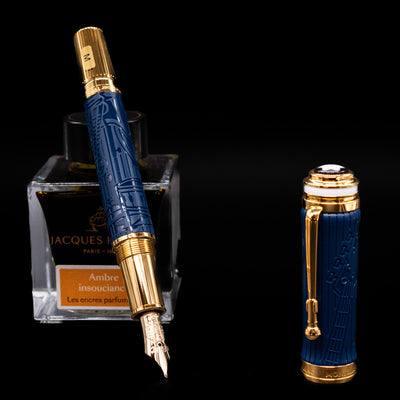 Montblanc Great Characters Homage to Queen Fountain Pen leaning on an ink bottle uncapped showcasing the detailing on the nib.