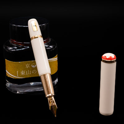 Montblanc Heritage Baby Ivory Fountain Pen leaning on an ink bottle uncapped showcasing the detailing on the nib.