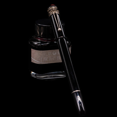 Montblanc Heritage Collection Metamorphosis Fountain Pen - Preowned capped, leaning against an ink bottle. 