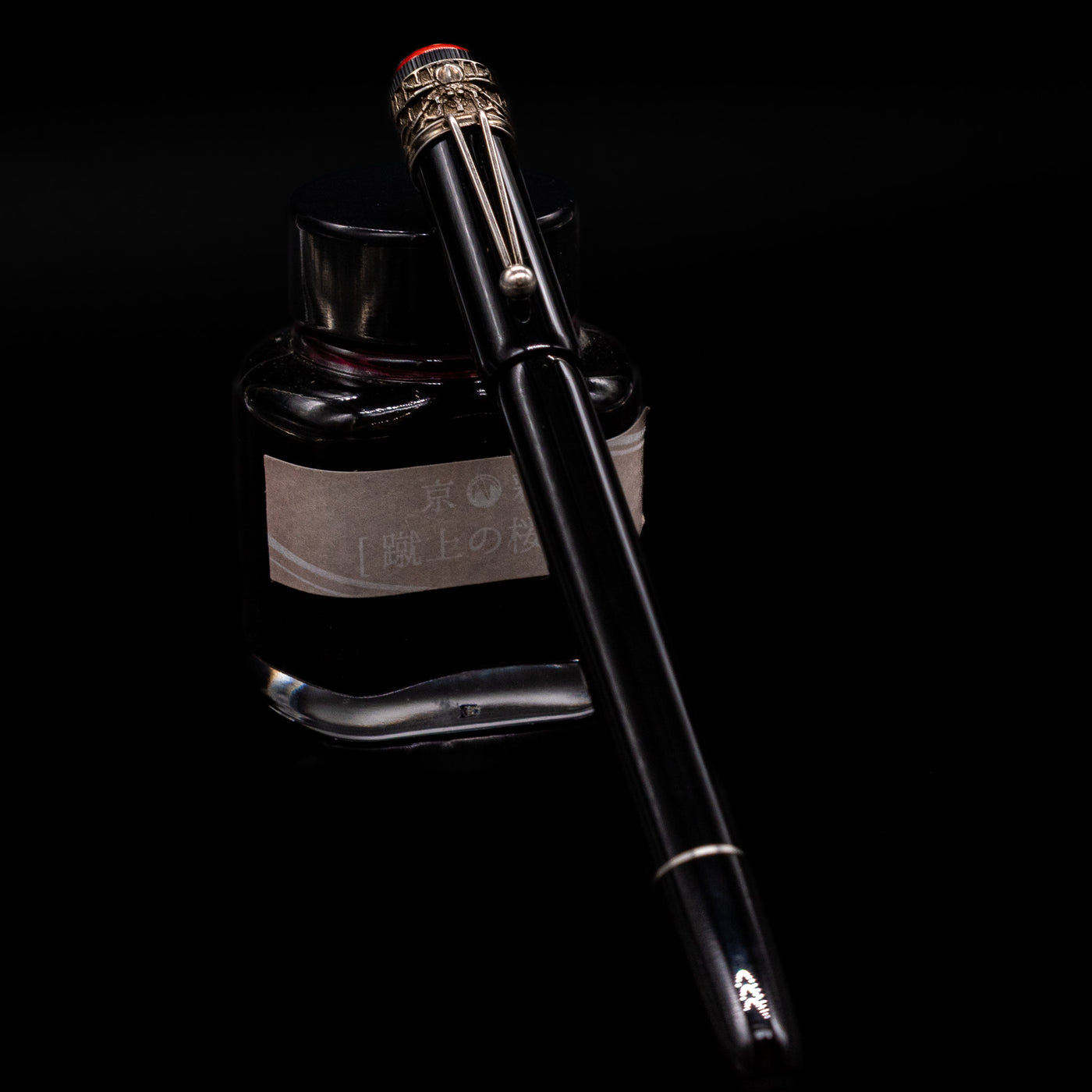 Montblanc Heritage Collection Metamorphosis Rollerball Pen - Preowned capped, leaning against an ink bottle. 