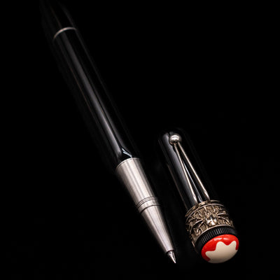 A full view of the Montblanc Heritage Collection Metamorphosis Rollerball Pen - Preowned uncapped, with its cap laying next to the pen. 