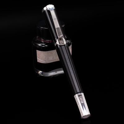 Montblanc John Lennon Special Edition Fountain Pen - Preowned capped, leaning against an ink bottle. 