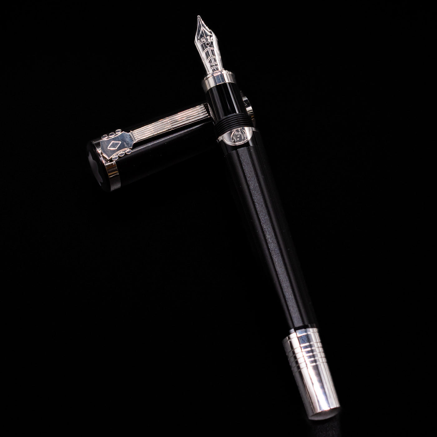 Montblanc John Lennon Special Edition Fountain Pen - Preowned laying on top of its cap in a crossed position showing full view of the entire uncapped pen.