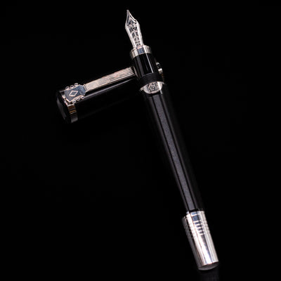 Montblanc John Lennon Special Edition Fountain Pen - Preowned laying on top of its cap in a crossed position showing full view of the entire uncapped pen.