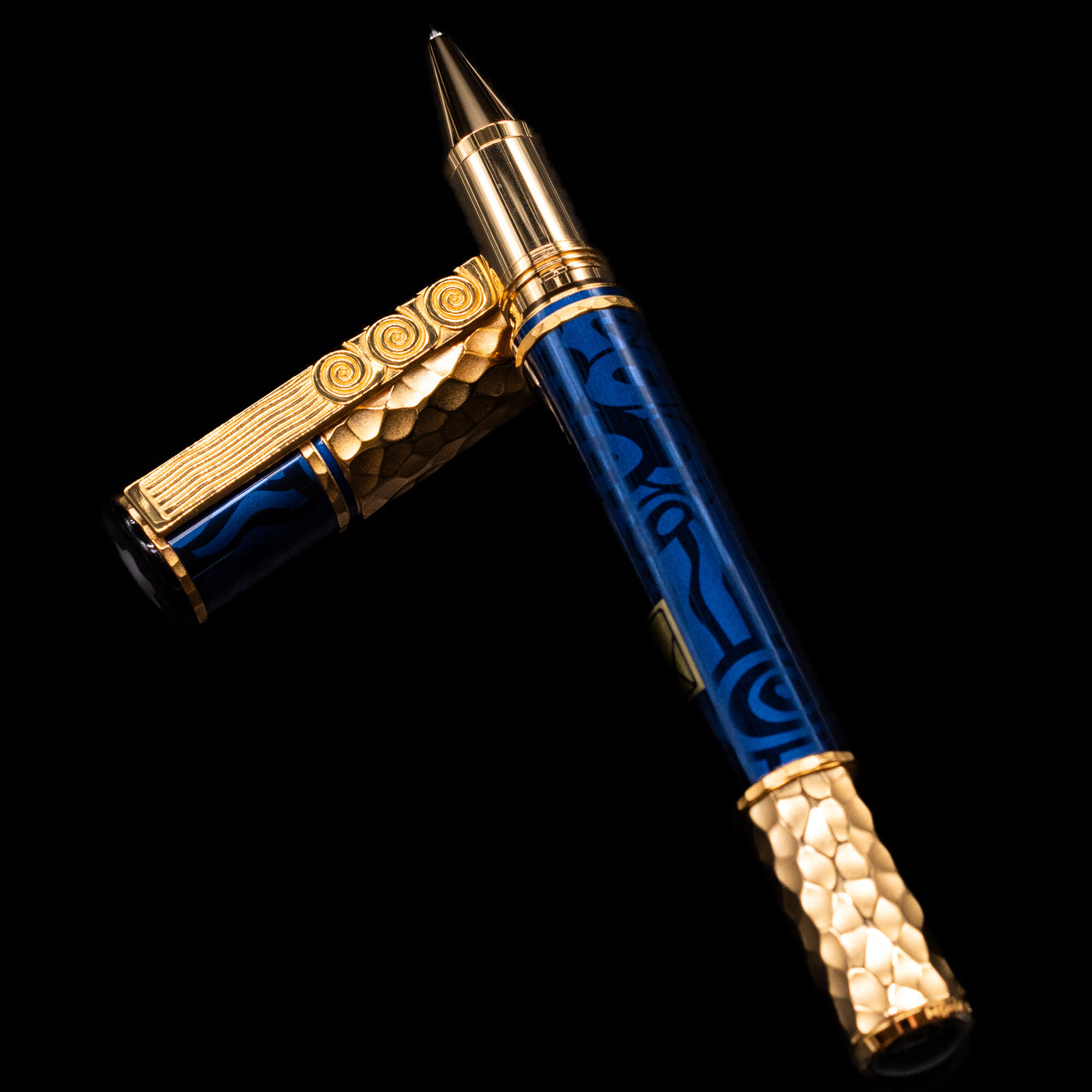Montblanc Masters of Art Homage to Gustav Klimt Limited Edition 4810 Rollerball Pen - Preowned  laying on top of its cap in a crossed position showing full view of the entire uncapped pen.