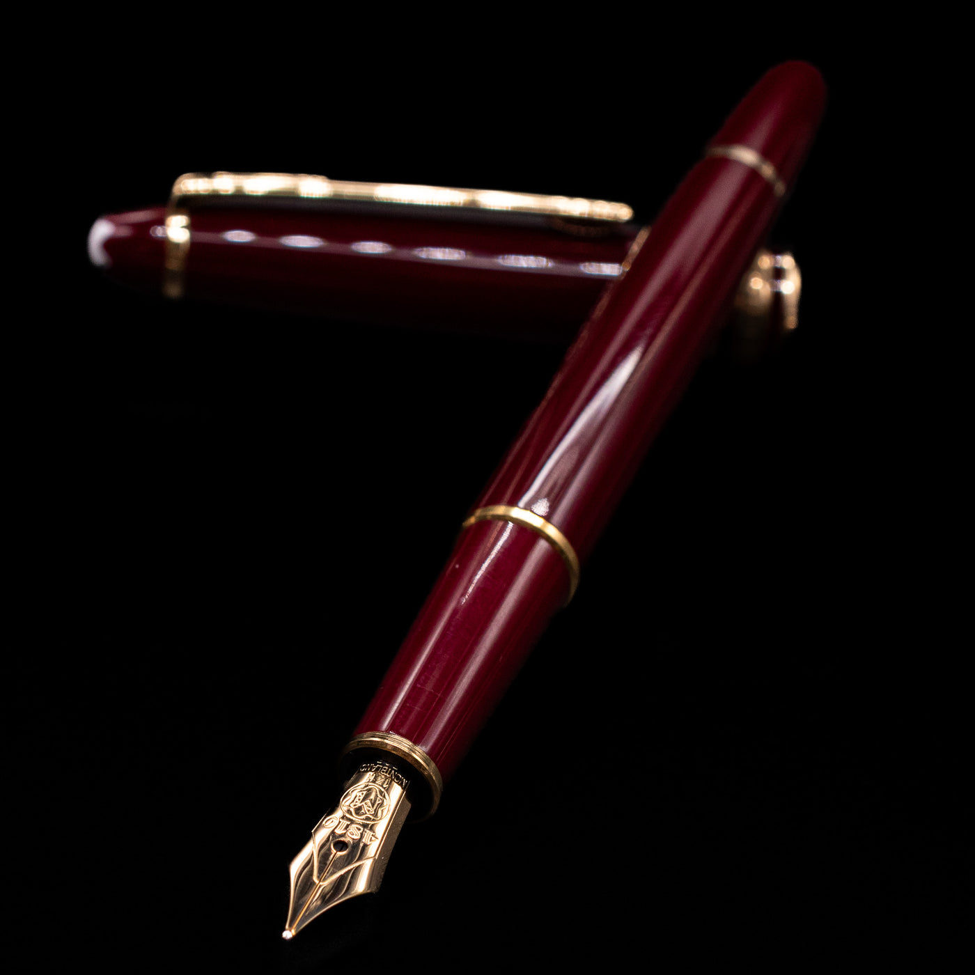 Montblanc Meisterstuck 144R Bordeaux Fountain Pen - Preowned laying across its own cap, crossed, with a focus on the nib.