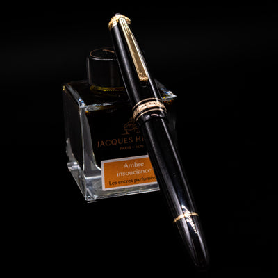 Montblanc Meisterstuck 146 75th Anniversary Special Edition LeGrand Fountain Pen - Preowned capped, leaning against an ink bottle. 