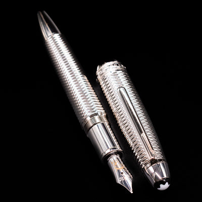 A full view of the Montblanc Meisterstuck 146 Solitaire Geometry City Edition LeGrand Fountain Pen - New York uncapped, with its cap laying next to the pen. 