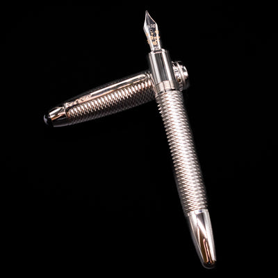 Montblanc Meisterstuck 146 Solitaire Geometry City Edition LeGrand Fountain Pen - Tokyo laying on top of its cap in a crossed position showing full view of the entire uncapped pen.