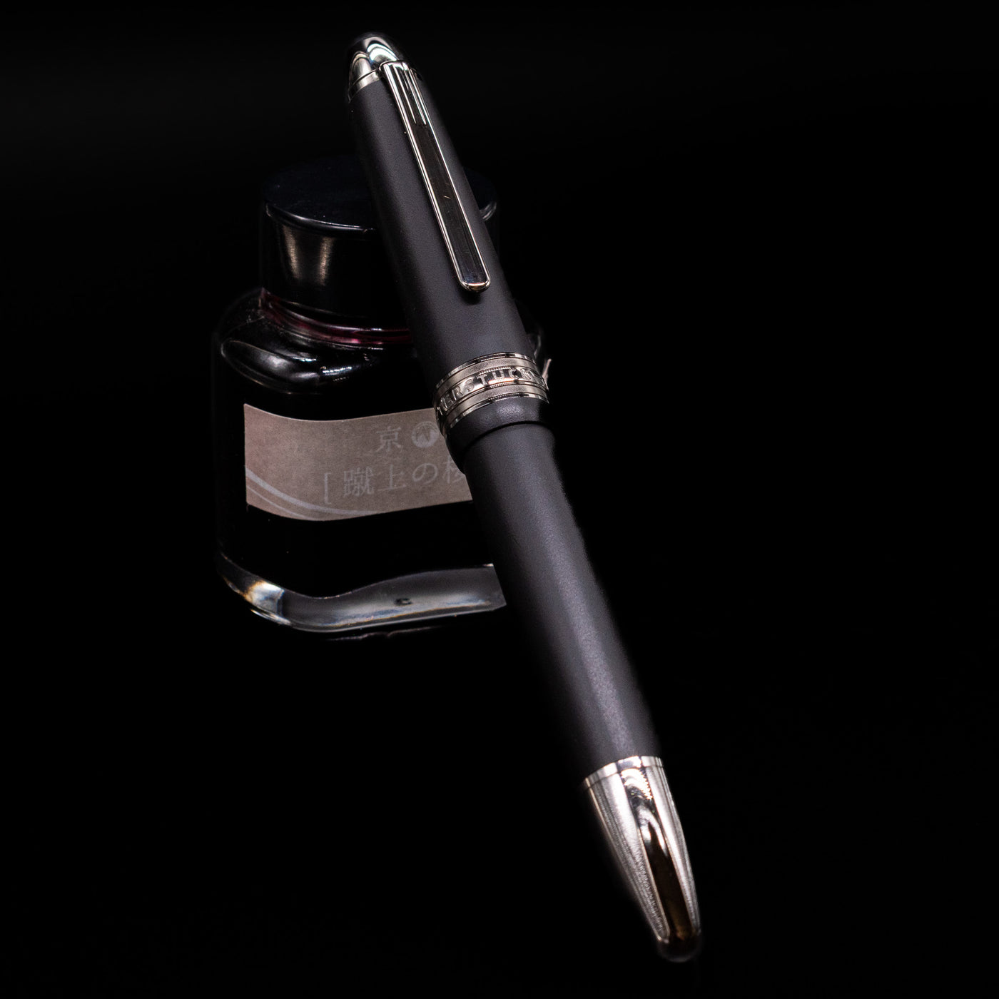 Montblanc Meisterstuck 146 Ultra Black LeGrand Fountain Pen - Preowned capped, leaning against an ink bottle. 