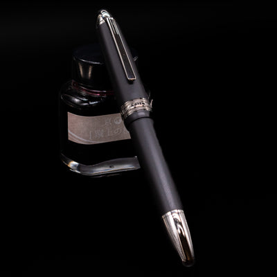 Montblanc Meisterstuck 146 Ultra Black LeGrand Fountain Pen - Preowned capped, leaning against an ink bottle. 