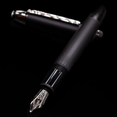 Montblanc Meisterstuck 146 Ultra Black LeGrand Fountain Pen - Preowned laying across its own cap, crossed, with a focus on the nib.