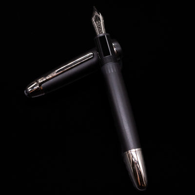 Montblanc Meisterstuck 146 Ultra Black LeGrand Fountain Pen - Preowned laying on top of its cap in a crossed position showing full view of the entire uncapped pen.