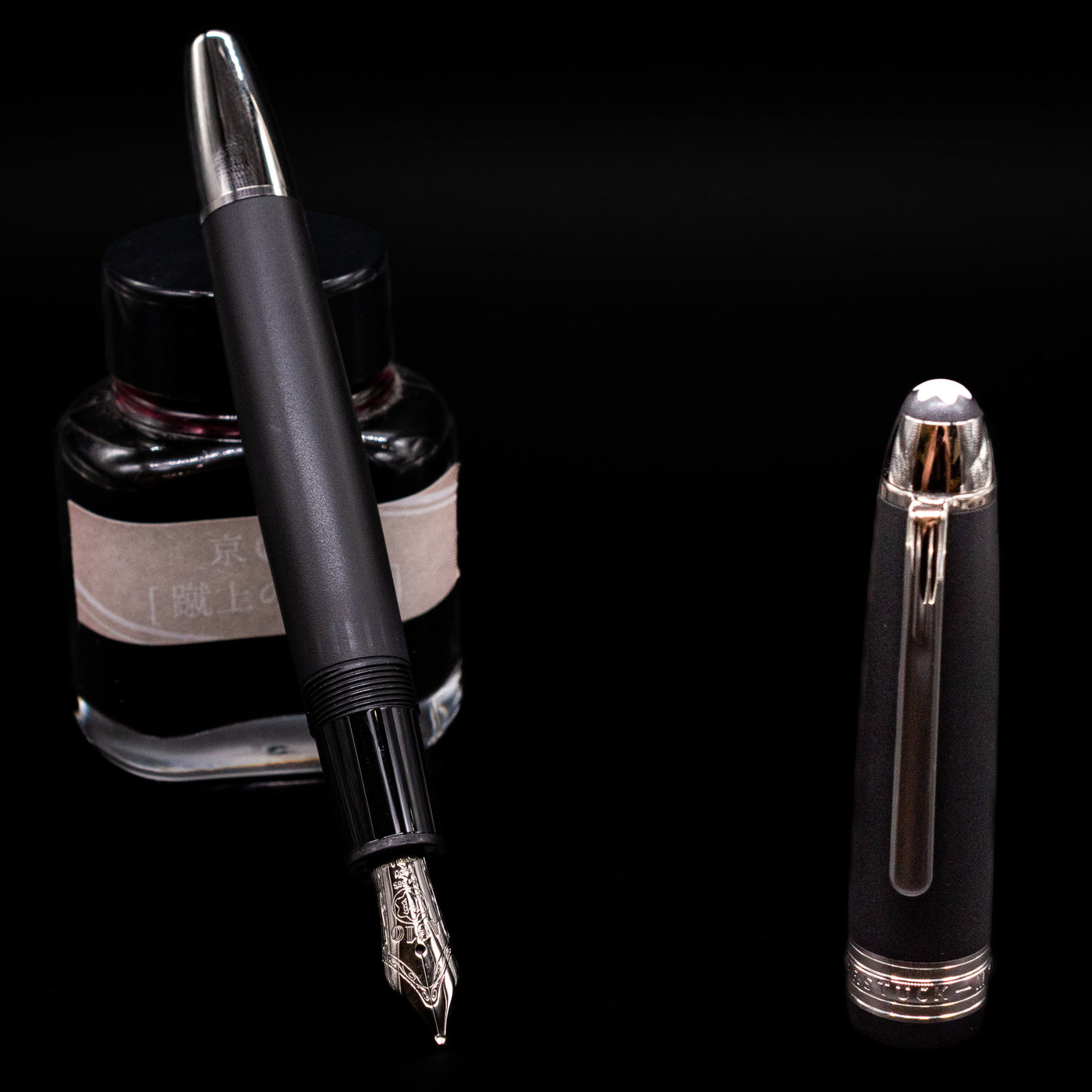 Montblanc Meisterstuck 146 Ultra Black LeGrand Fountain Pen - Preowned leaning on an ink bottle uncapped showcasing the detailing on the nib.