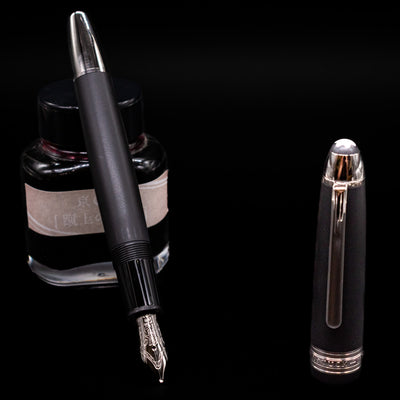 Montblanc Meisterstuck 146 Ultra Black LeGrand Fountain Pen - Preowned leaning on an ink bottle uncapped showcasing the detailing on the nib.
