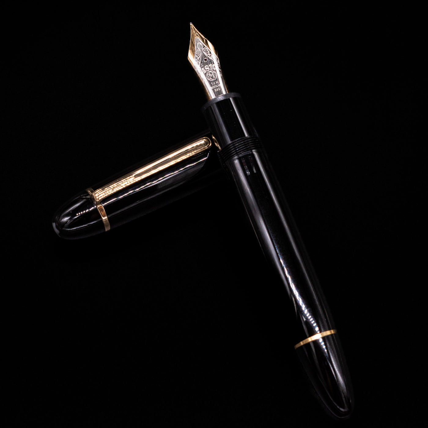 Preowned Montblanc Meisterstück 149 fountain pen and cap arranged in a crossed position, showcasing the pen’s balanced proportions, glossy black finish, and signature gold trim.