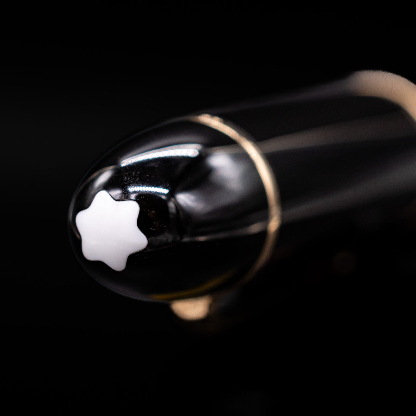 Close-up of the cap top on the preowned Montblanc Meisterstück 149 fountain pen, featuring the white Montblanc snowcap emblem set into the glossy black resin finial.