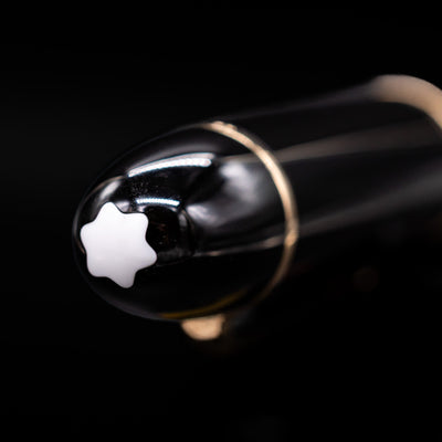 Close-up of the cap top on the preowned Montblanc Meisterstück 149 fountain pen, featuring the white Montblanc snowcap emblem set into the glossy black resin finial.