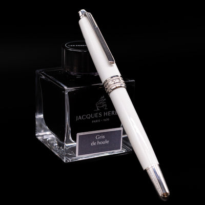 Preowned Montblanc Meisterstück 163 Solitaire Tribute to Mont Blanc rollerball pen shown capped, resting at an angle against an ink bottle.