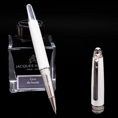 Preowned Montblanc Meisterstück 163 Solitaire Tribute to Mont Blanc rollerball pen displayed uncapped, leaning on an ink bottle to reveal the smooth rollerball tip.