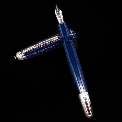 Preowned Montblanc Meisterstück Le Petit Prince Fox LeGrand fountain pen and cap arranged in a crossed position, highlighting the fox engraving on the cap and the elegant blue resin finish.
