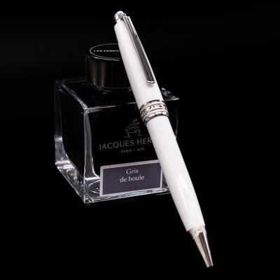 Preowned Montblanc Meisterstück Solitaire Tribute to Mont Blanc ballpoint pen resting at an angle against an ink bottle.