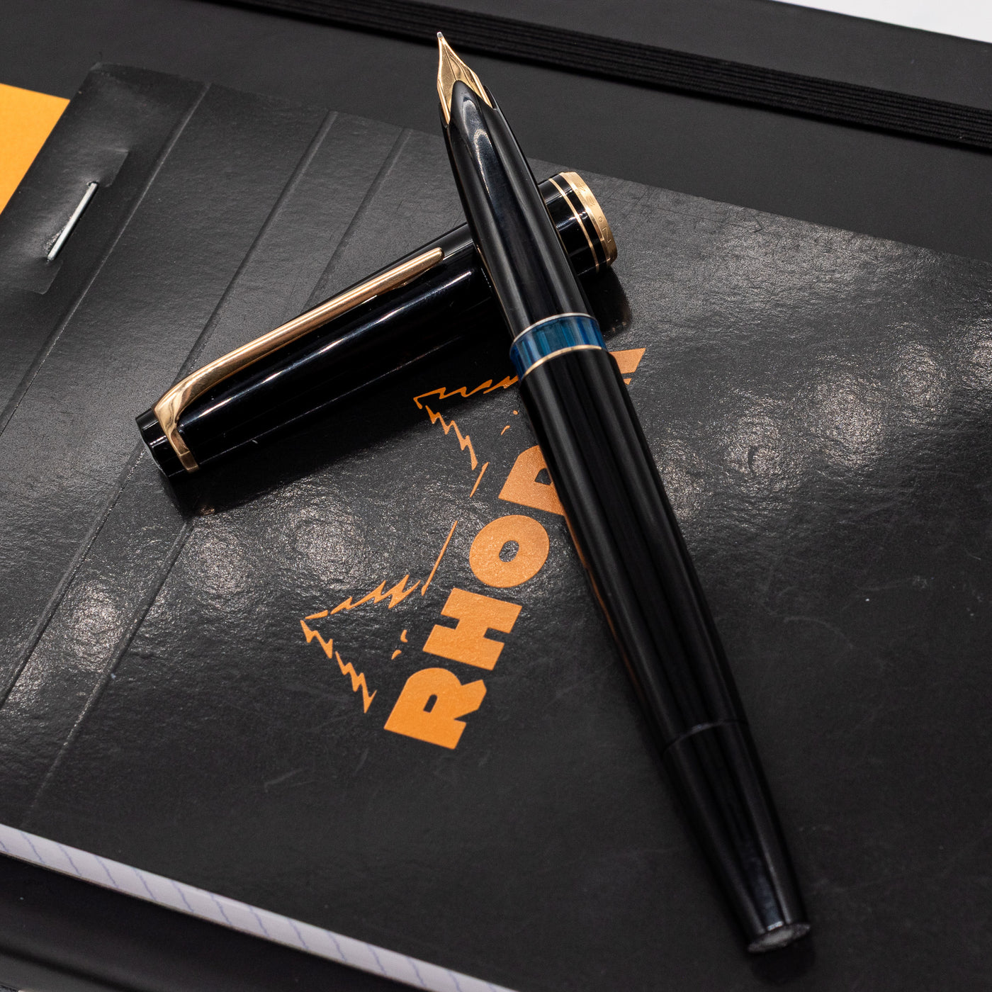 Montblanc No. 24 black and gold fountain pen uncapped on Rhodia notebook – 14k gold nib and transparent blue ink window featured