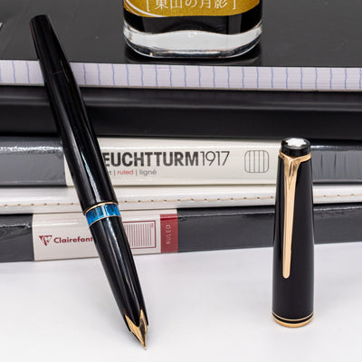 Montblanc No. 24 black fountain pen with gold trim and cap displayed beside Leuchtturm and Clairefontaine notebooks – vintage piston-filled pen