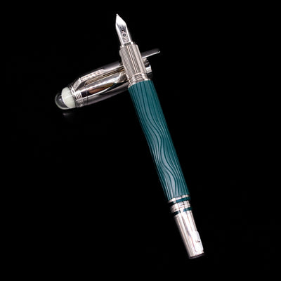 Montblanc Starwalker Doue Fountain Pen - Polar Green laying on top of its cap in a crossed position showing full view of the entire uncapped pen.