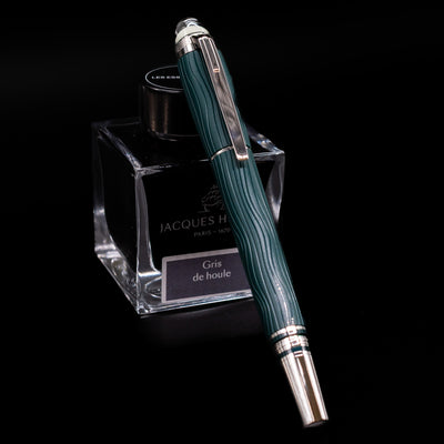 Montblanc Starwalker Resin Fountain Pen - Polar Green capped, leaning against an ink bottle. 
