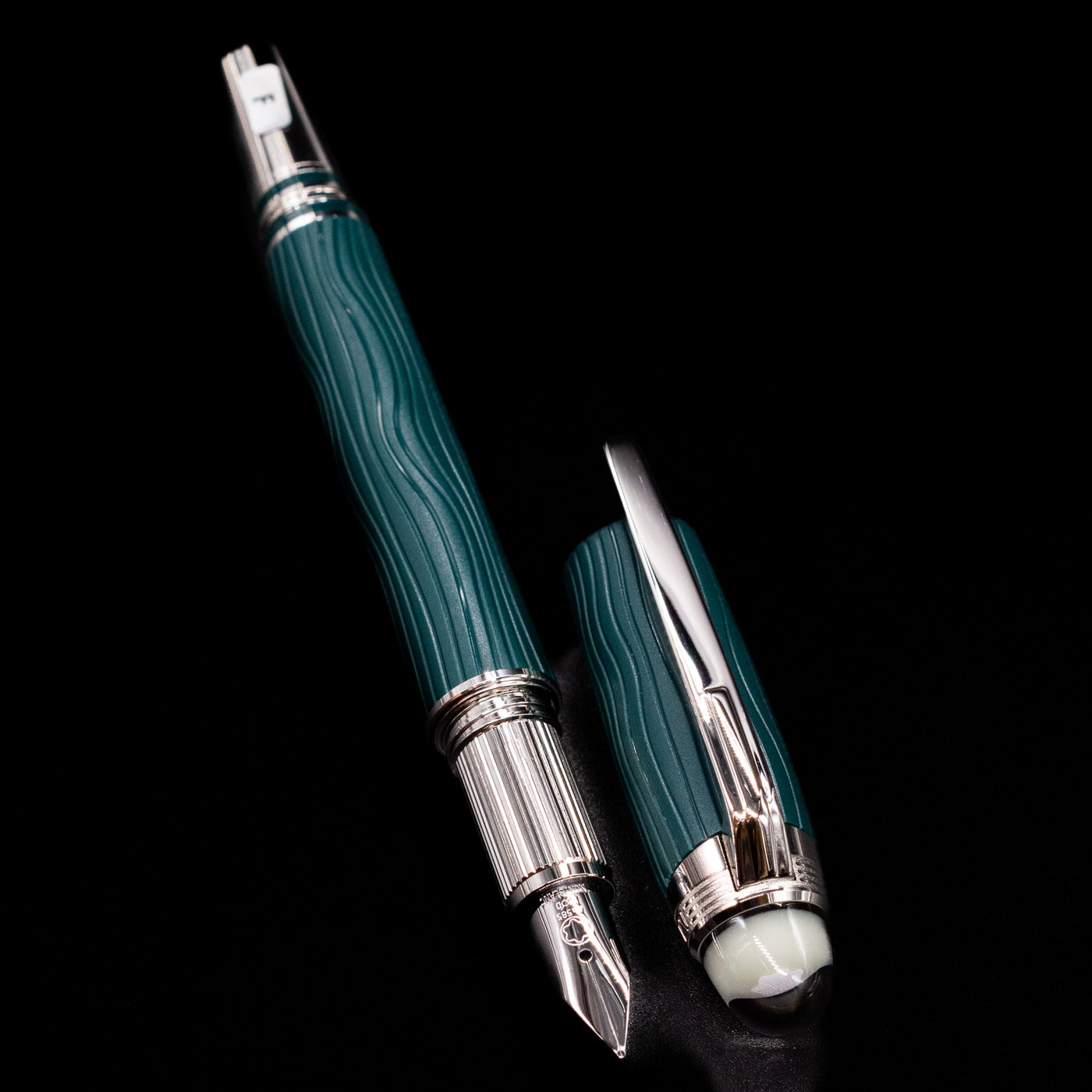 A full view of the Montblanc Starwalker Resin Fountain Pen - Polar Green uncapped, with its cap laying next to the pen. 