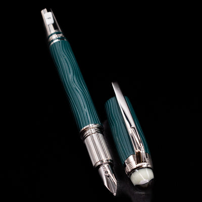 A full view of the Montblanc Starwalker Resin Fountain Pen - Polar Green uncapped, with its cap laying next to the pen. 