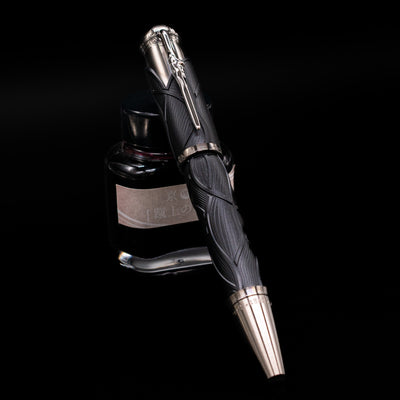 Montblanc Writer's Edition Brothers Grimm Fountain Pen capped, leaning against an ink bottle. 