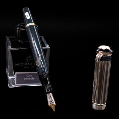 Montblanc Writer's Edition Charles Dickens Fountain Pen - Preowned leaning on an ink bottle uncapped showcasing the detailing on the nib.