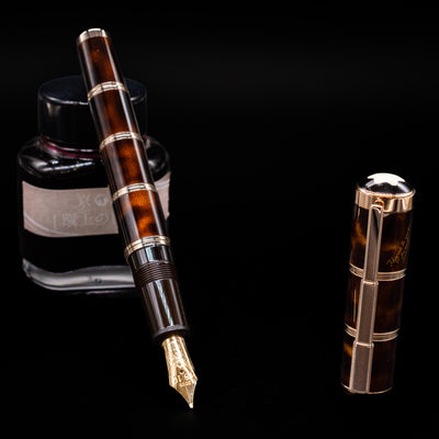 Montblanc Writer's Edition Miguel de Cervantes Fountain Pen - Preowned leaning on an ink bottle uncapped showcasing the detailing on the nib.