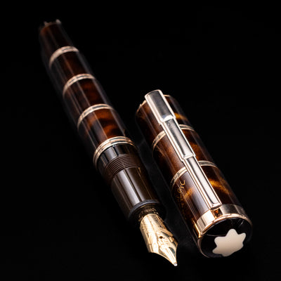 A full view of the Montblanc Writer's Edition Miguel de Cervantes Fountain Pen - Preowned uncapped, with its cap laying next to the pen. 